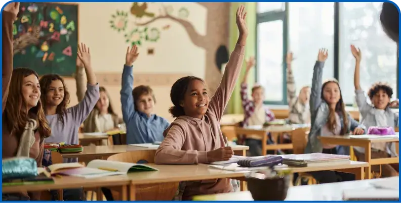 Students in a classroom with hands raised during a lesson